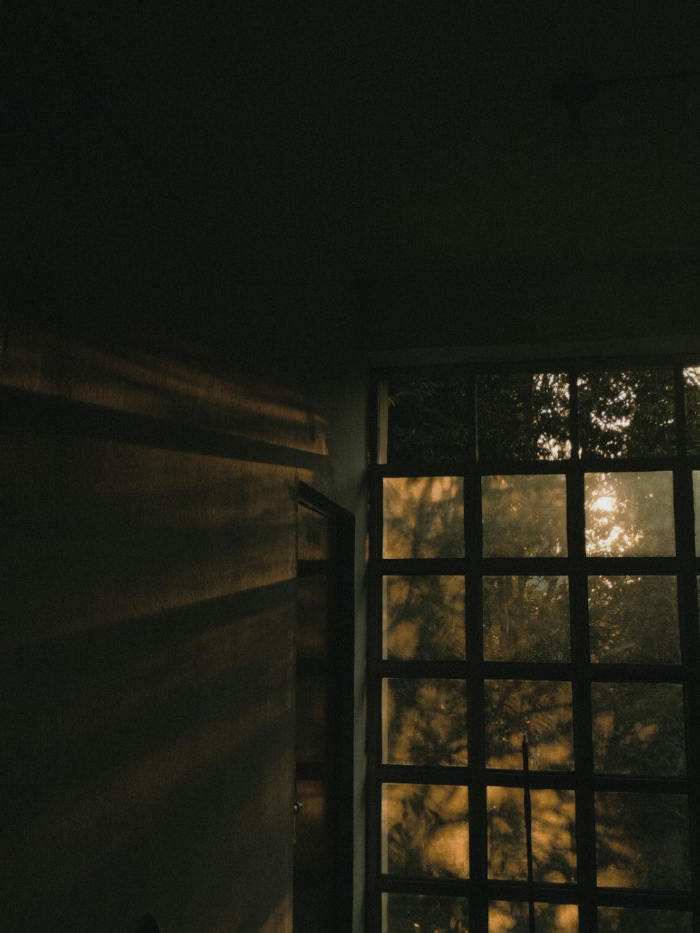 a dark room with a window and a light coming through the window