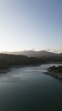 A serene photo of a large lake surrounded by forest under a clear sky