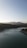 A serene landscape with a calm lake reflecting mountains under a clear blue sky.