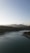A serene landscape with a calm lake reflecting mountains under a clear blue sky.