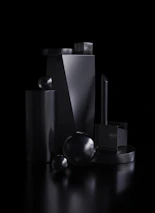Abstract monochrome 3D metal and glass forms casting bold shadows on black background.