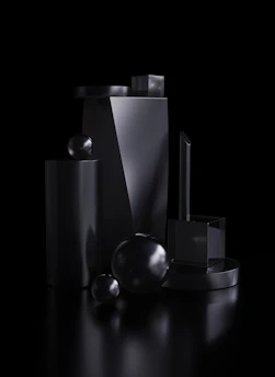 Abstract monochrome 3D metal and glass forms casting bold shadows on black background.