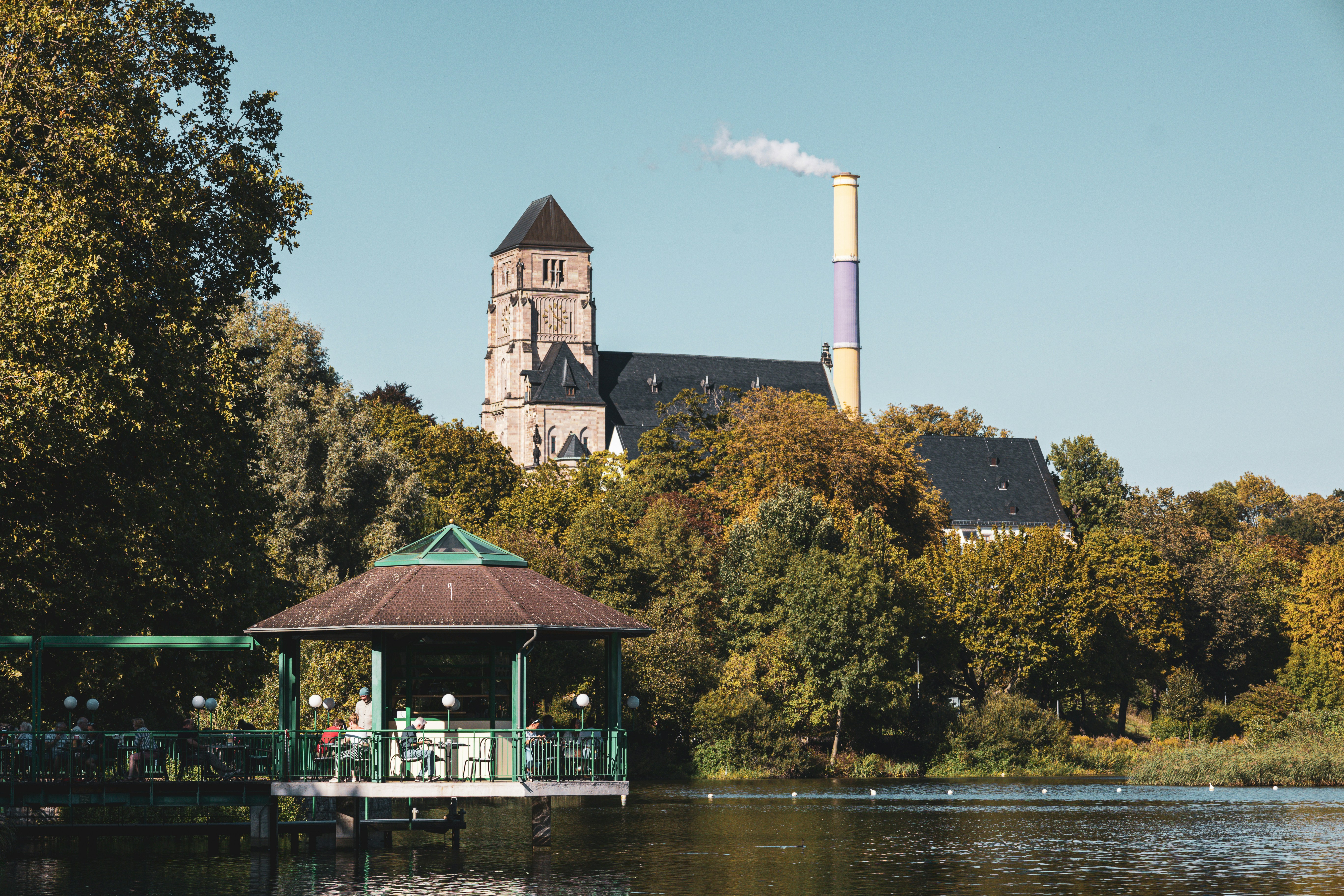 a gazebo on a lake with a building in the background