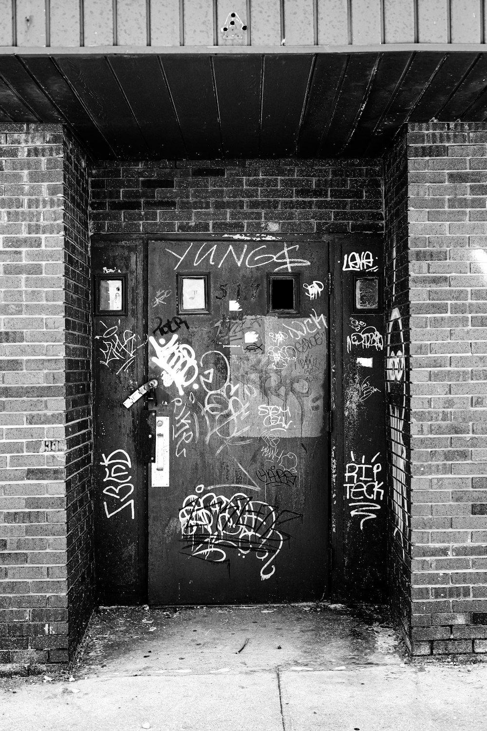 a black and white photo of a door with graffiti on it