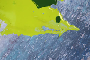 A close-up of a textured paint splash with bright yellows and greens swirling together.