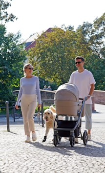 a man and woman walking with a dog in a stroller