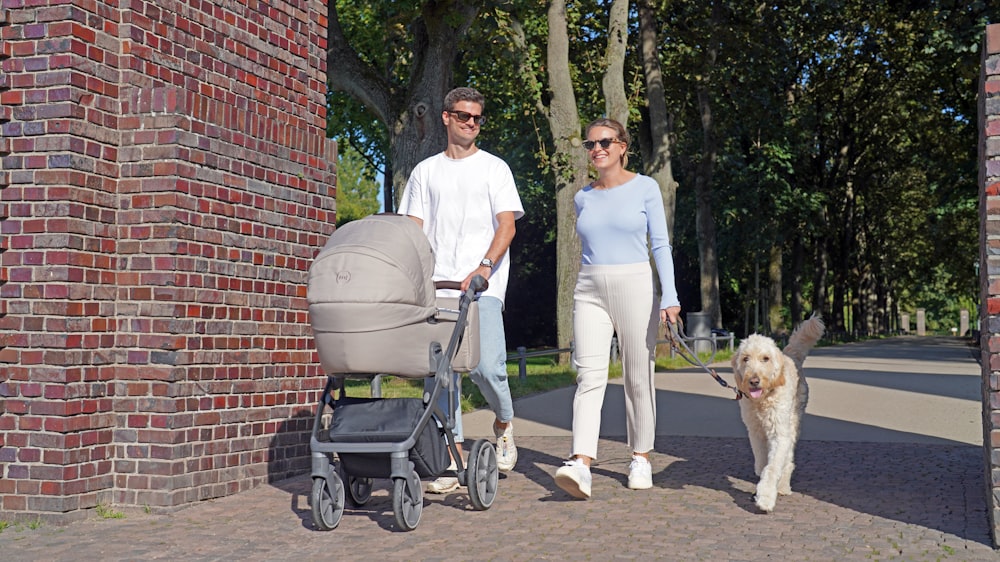 a man and a woman walking a dog and a stroller