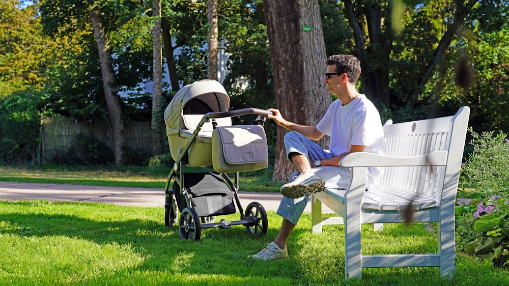 a man sitting on a bench next to a baby stroller