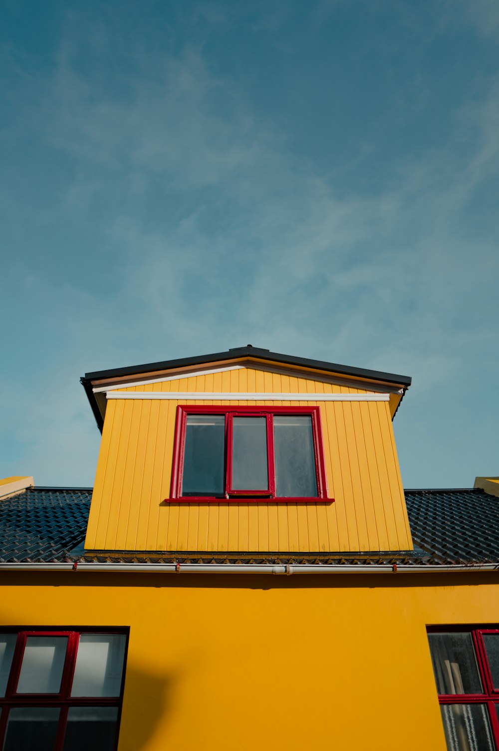 a yellow building with red windows and a black roof