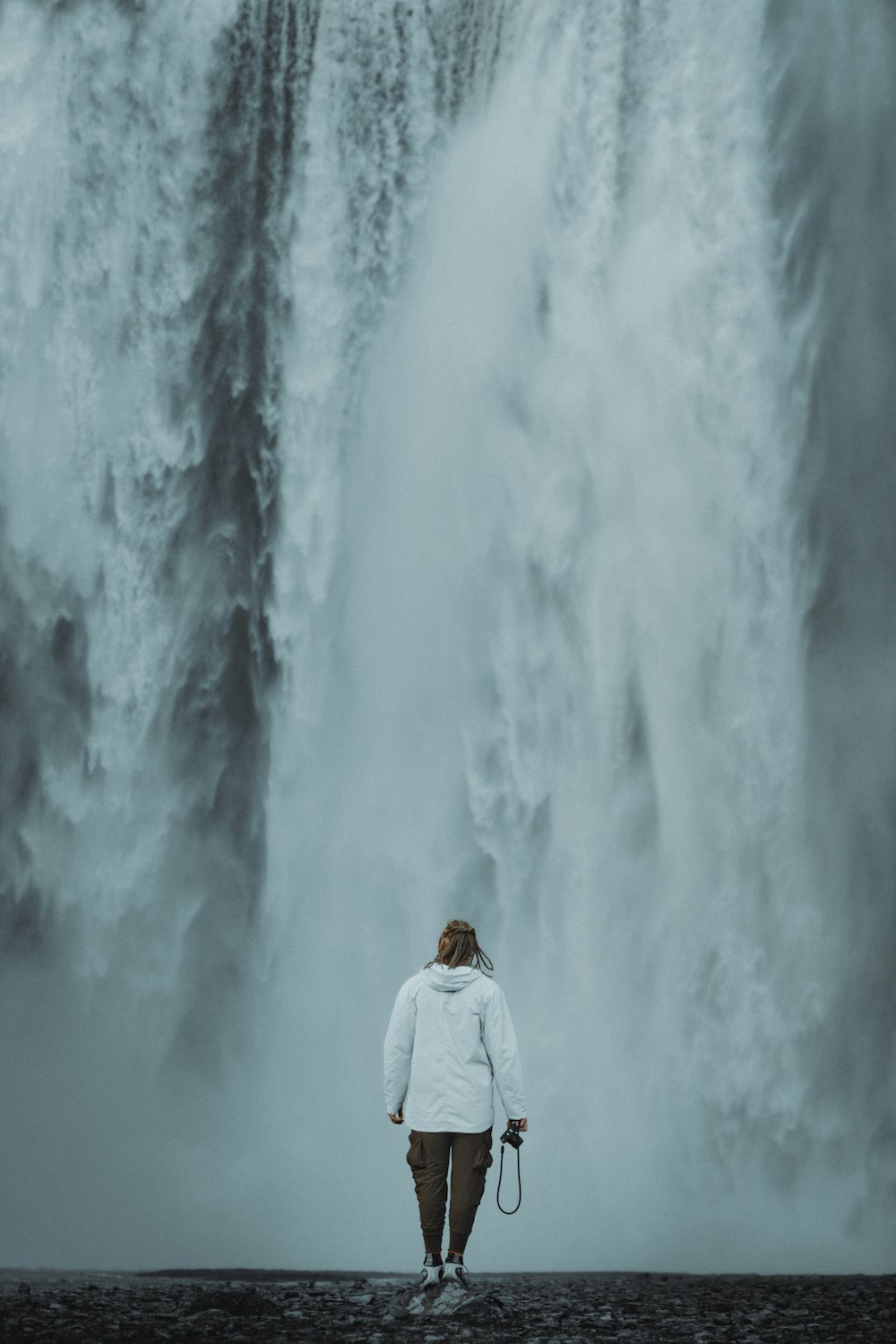 a person standing in front of a large waterfall