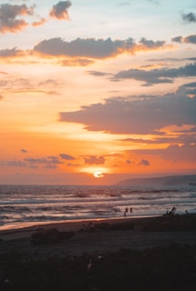 A vibrant sunset over a serene beach with travelers enjoying the view