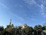 A peaceful mosque surrounded by greenery under a blue sky.
