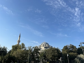 Soft morning light illuminating the mosque’s elegant green and gold dome against a clear sky