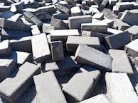 Rows of 4x8x16 concrete blocks arranged outdoors under bright sunlight.