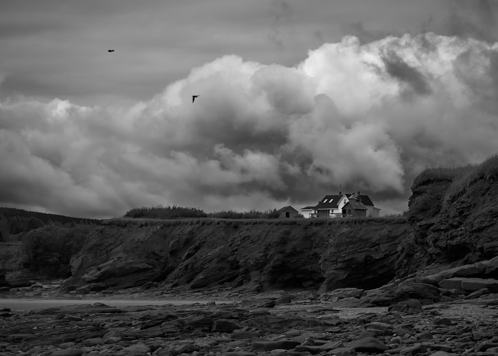 Une photo en noir et blanc d’une maison sur une falaise