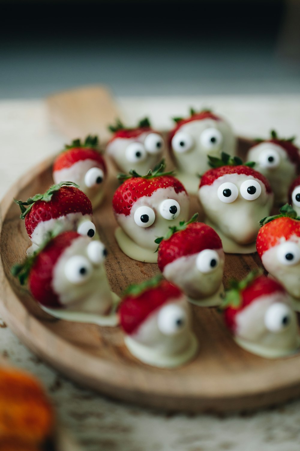 a wooden plate topped with strawberries covered in googly eyes