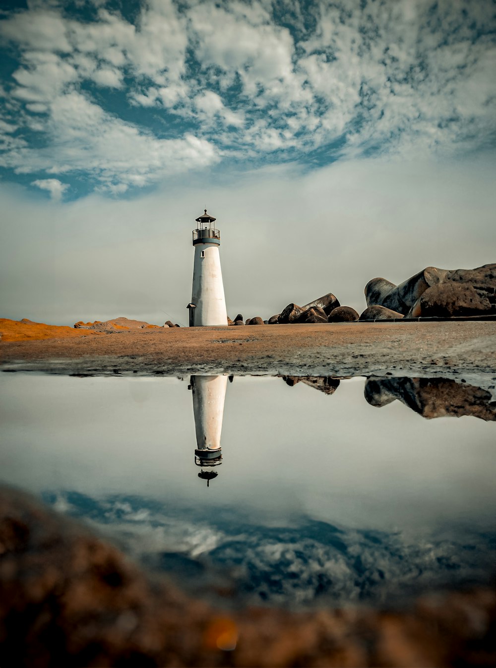 a white lighthouse sitting on top of a sandy beach