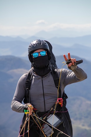 A smiling customer wearing a helmet, ready for a paramotor flight with the scenic Shillong landscape behind.