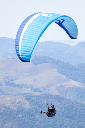 An instructor guiding a student during a tandem paragliding flight over Taiwan's mountains