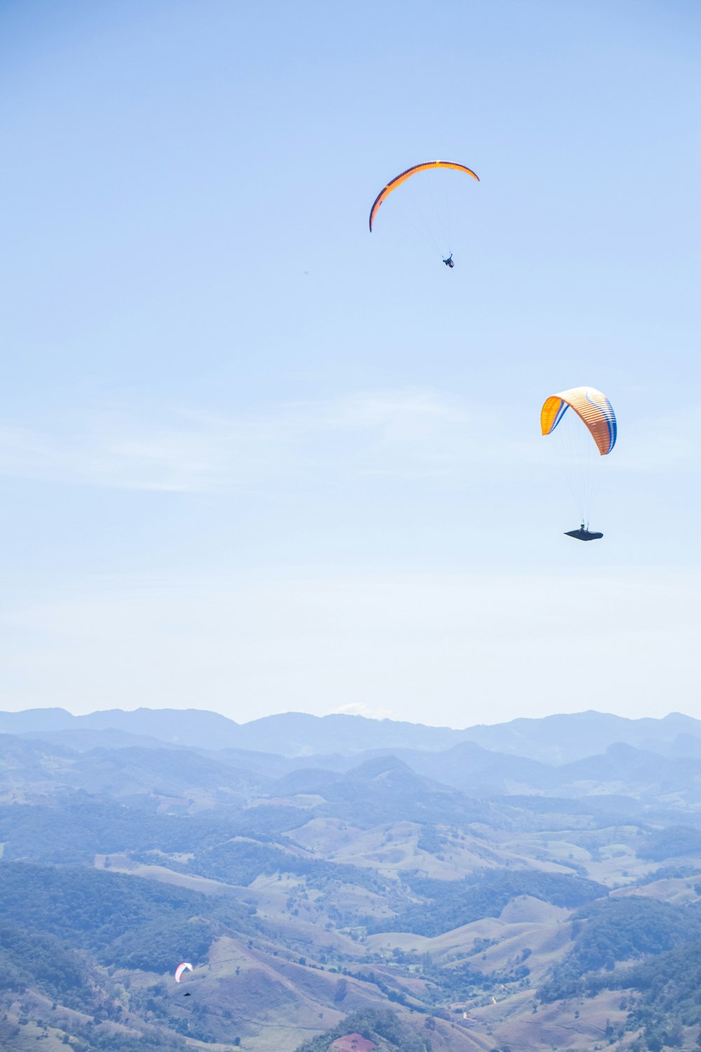 a group of people flying kites over a lush green hillside