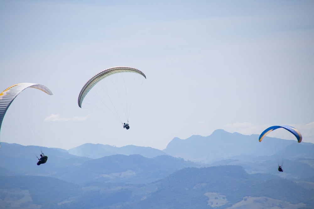 a group of people parasailing over a mountain range