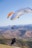a man flying a large kite over a lush green hillside