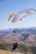 a man flying a large kite over a lush green hillside
