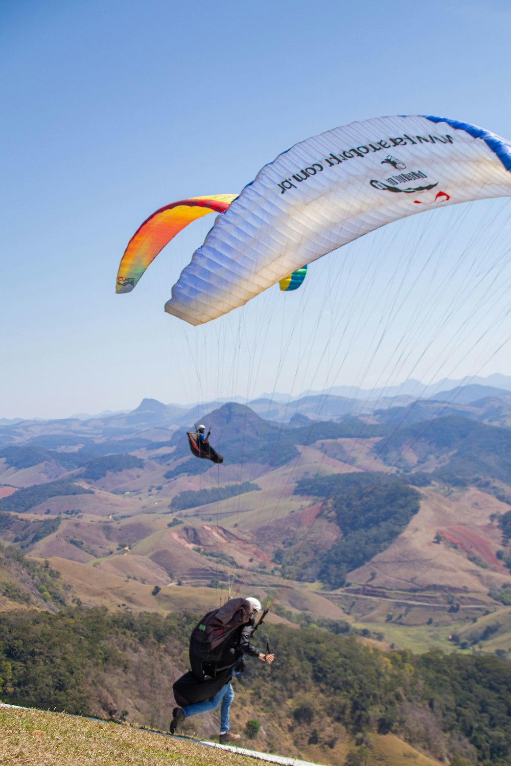 a man flying a large kite over a lush green hillside