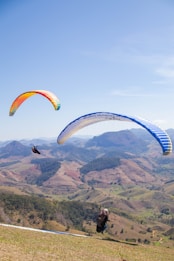 two people are paragliding over a mountain range