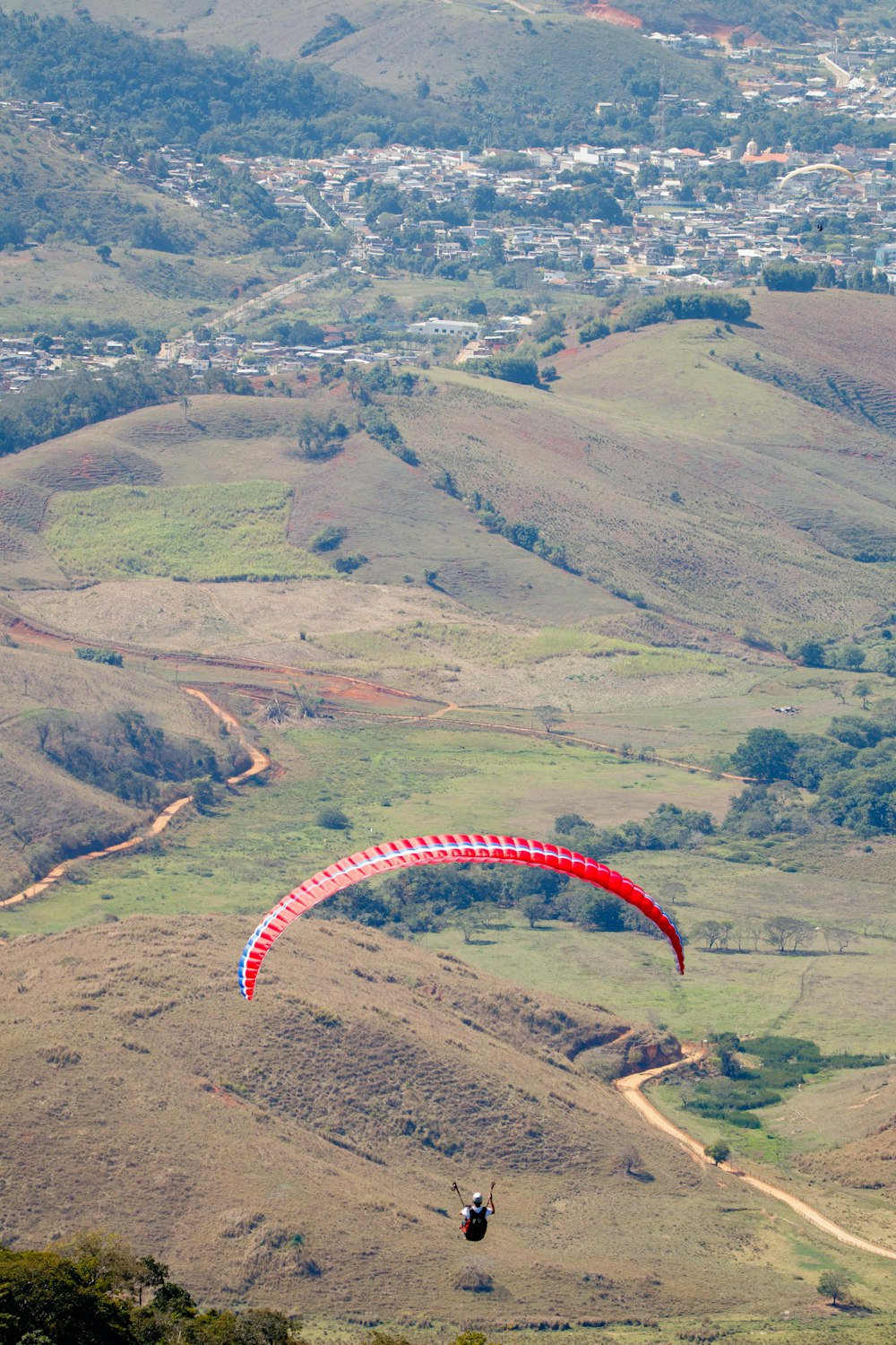 a person paragliding over a lush green hillside