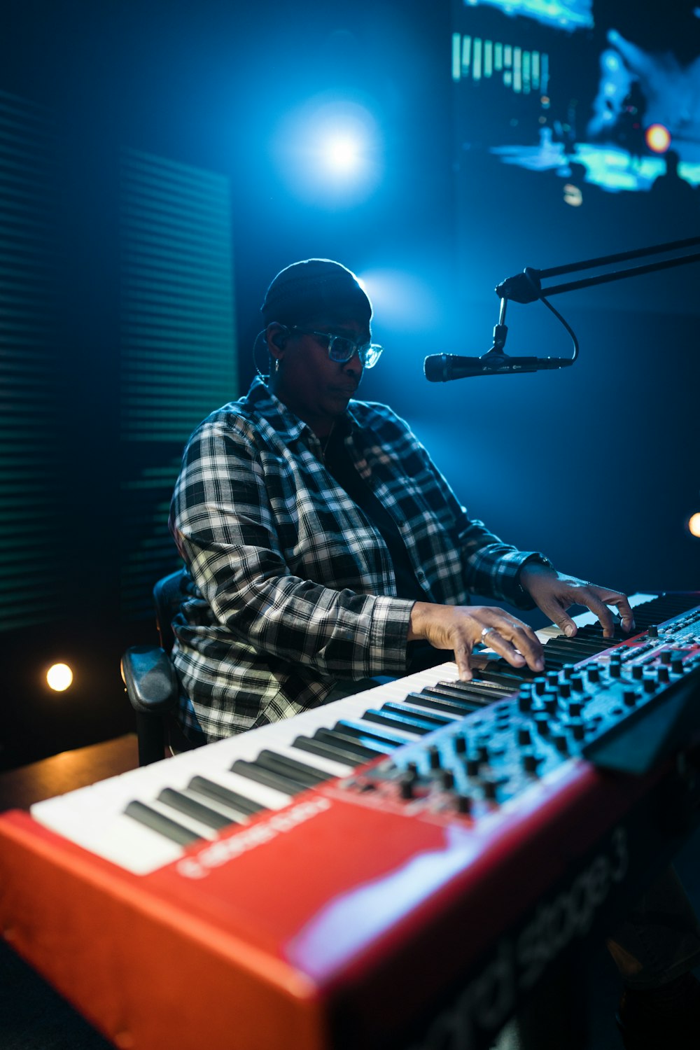 a man sitting at a keyboard in front of a microphone