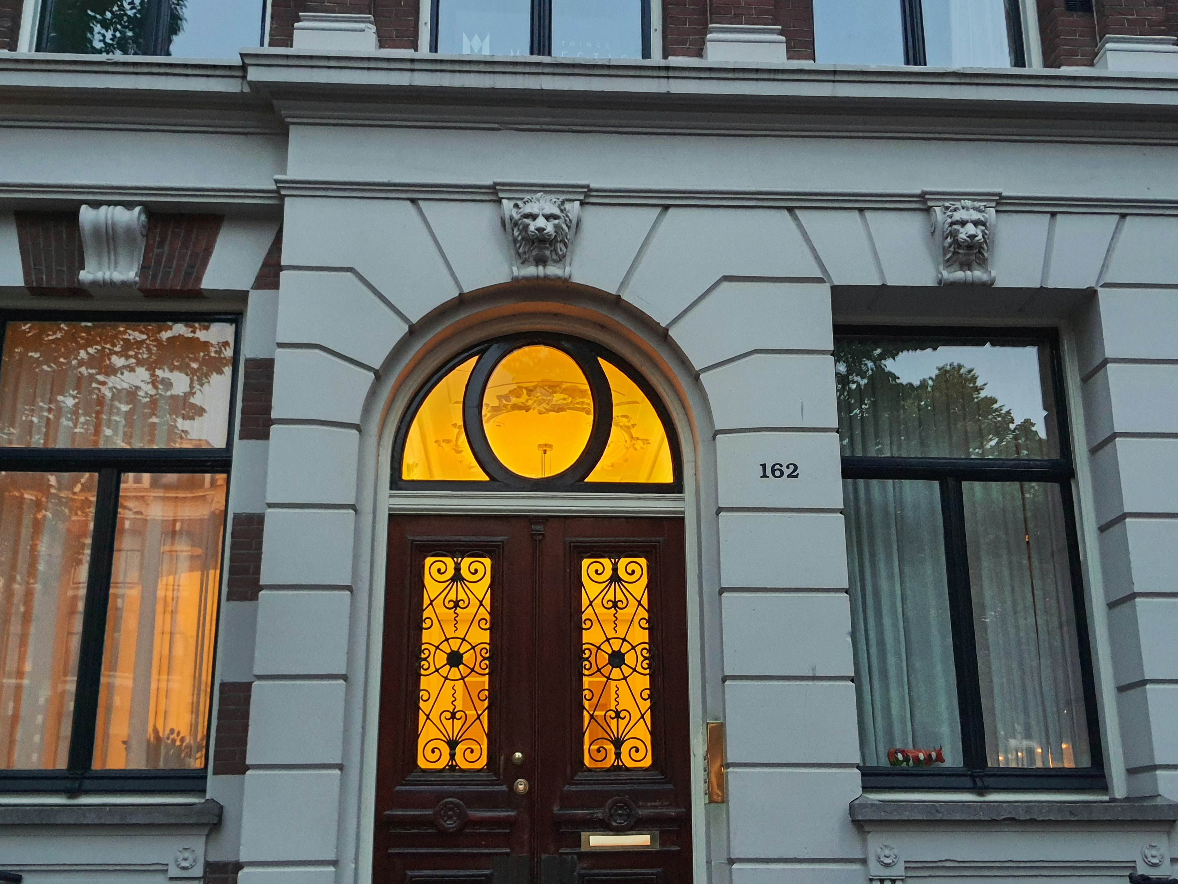 a white building with a brown door and two windows