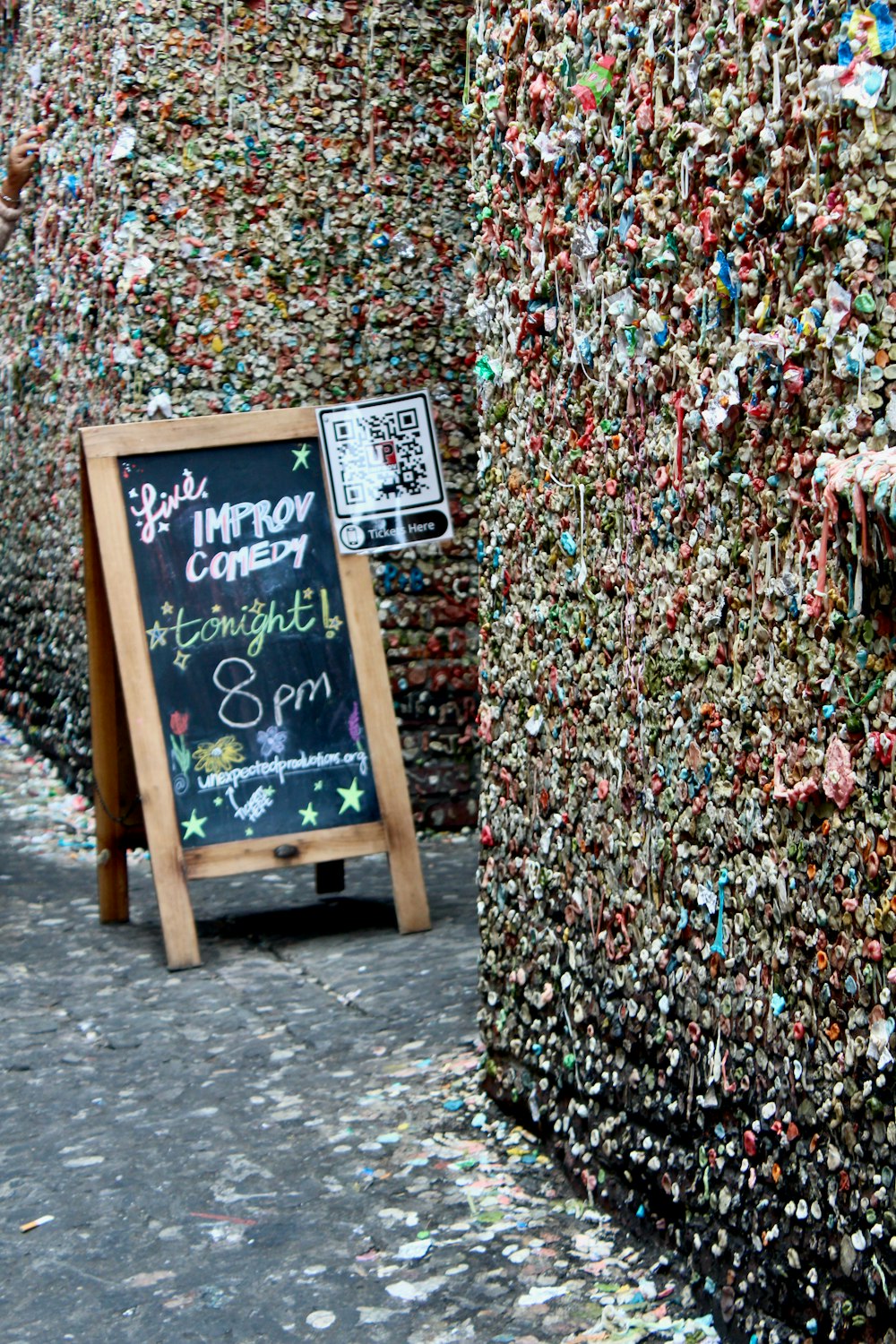 a chalkboard with a sign in front of a wall covered in confetti