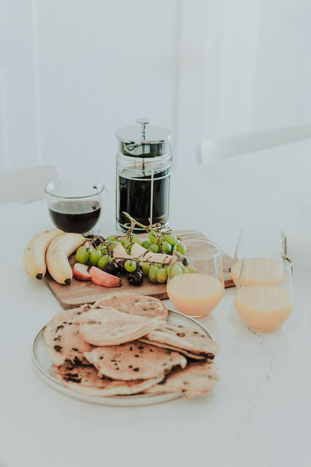 a white table topped with a plate of food and glasses of wine