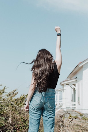 a woman standing in front of a house with her arms in the air