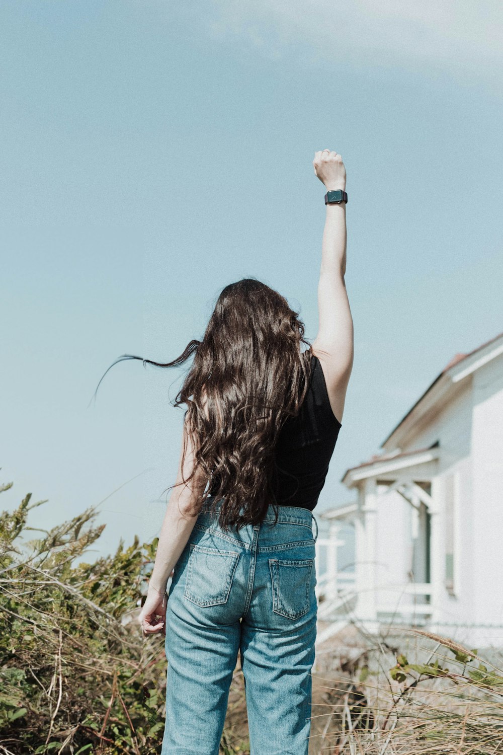 a woman standing in front of a house with her arms in the air