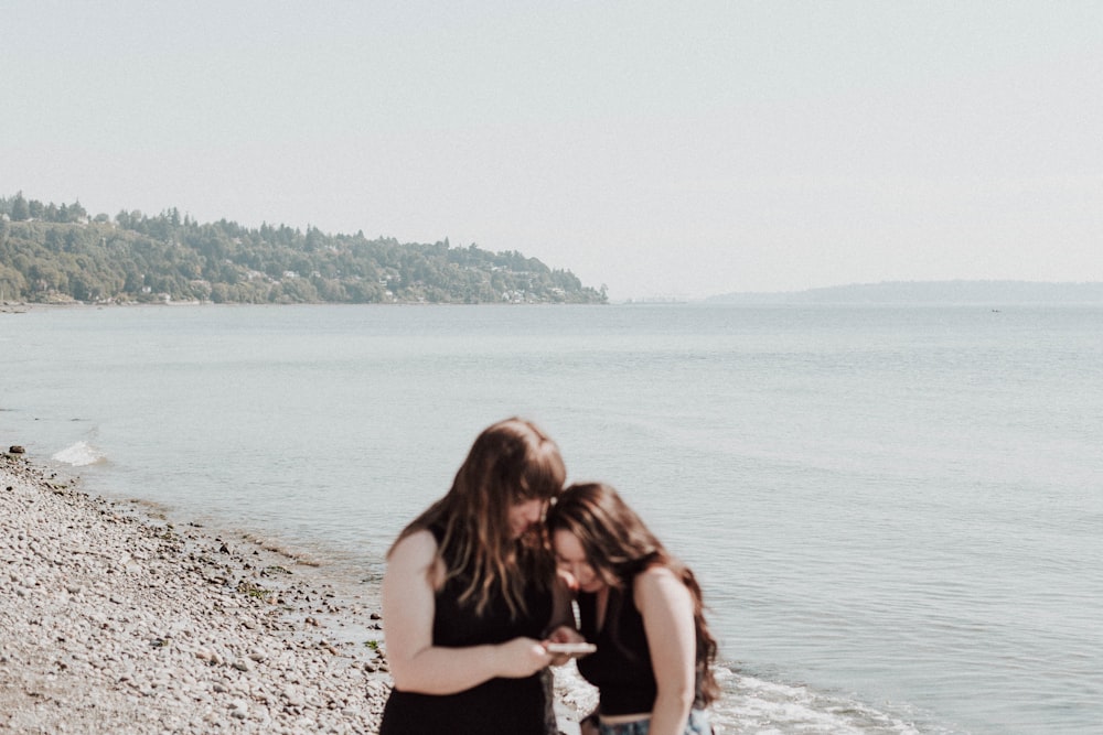 a couple of women standing next to each other on a beach