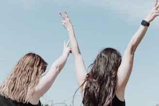 two women reaching up to catch a frisbee