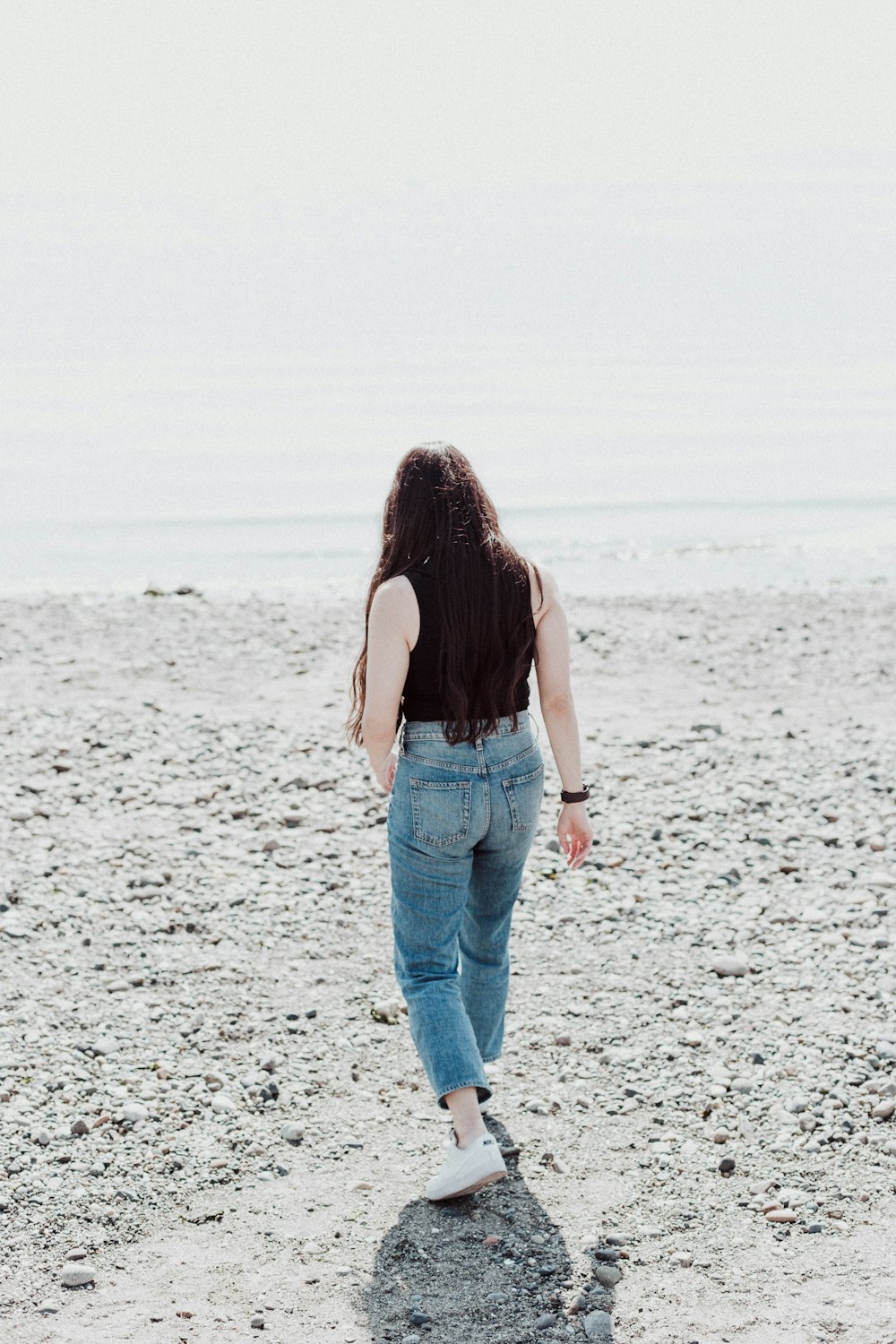 a woman walking across a sandy beach next to the ocean