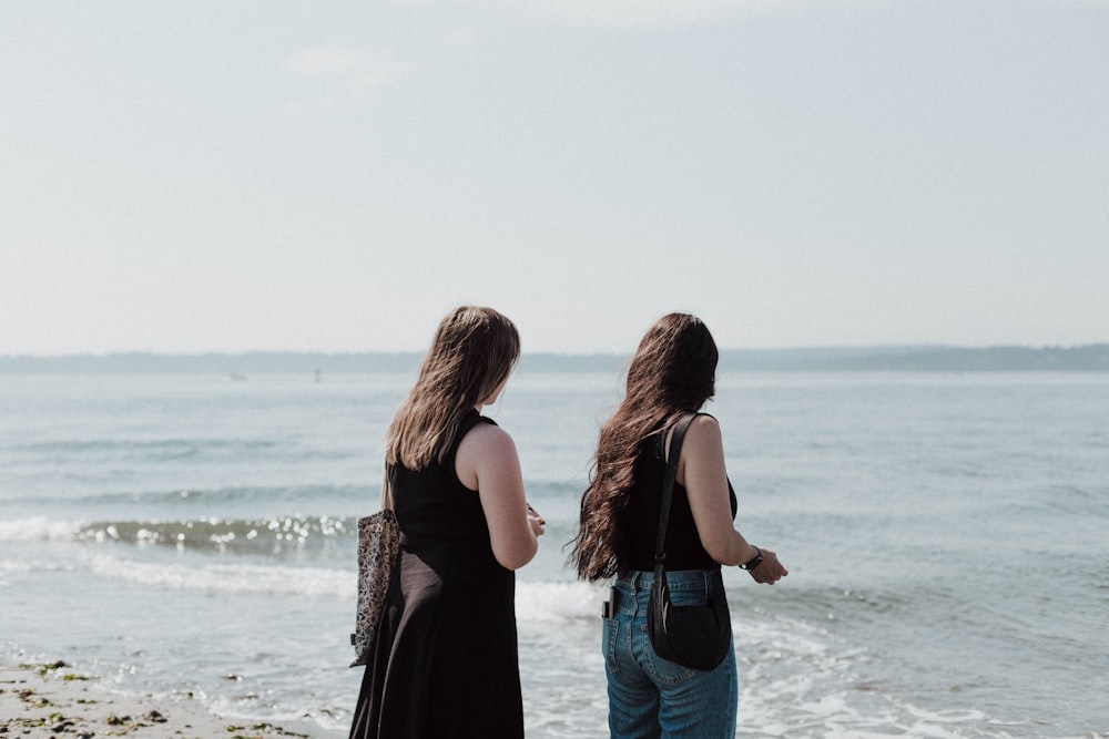 a couple of women standing on top of a beach