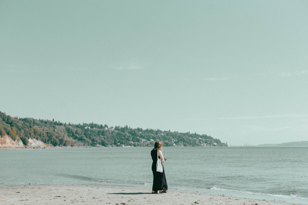 a woman standing on a beach next to the ocean