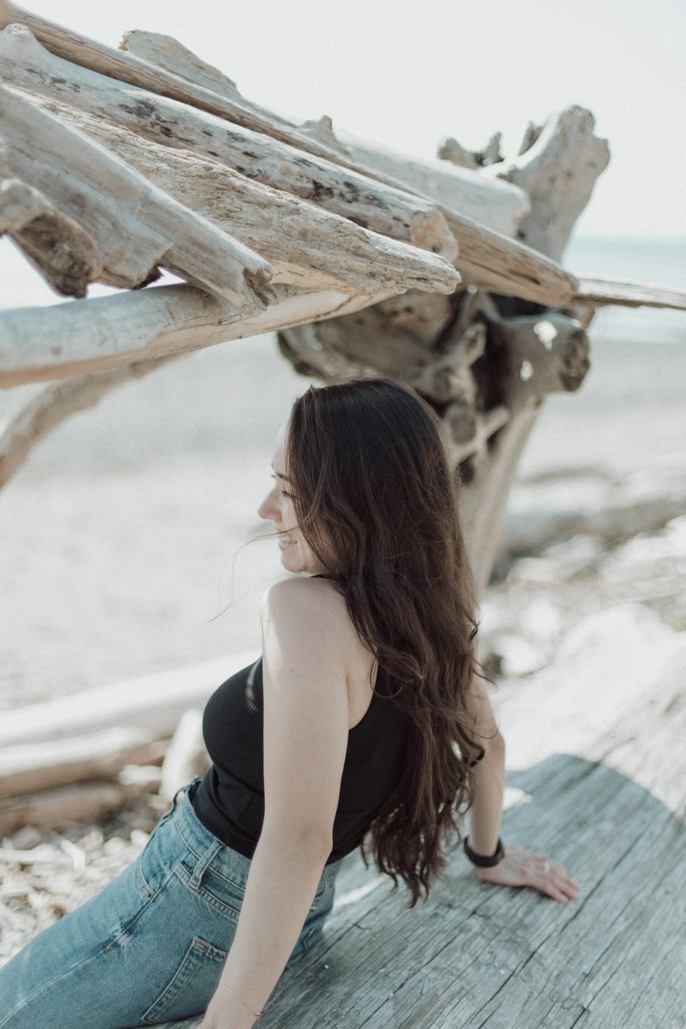 a woman sitting on a wooden bench next to a body of water