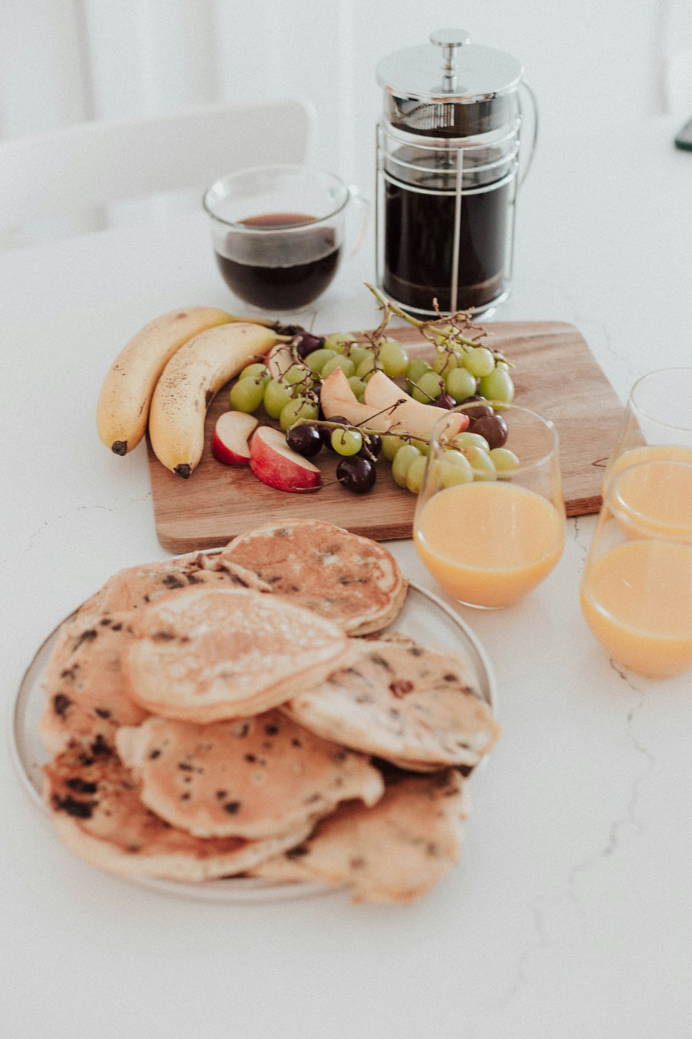 a white table topped with plates of food and glasses of orange juice