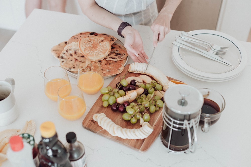 a woman cutting up a platter of food on a table