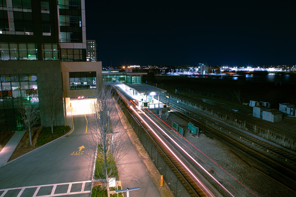 Un tren que viaja por las vías del tren junto a un edificio alto