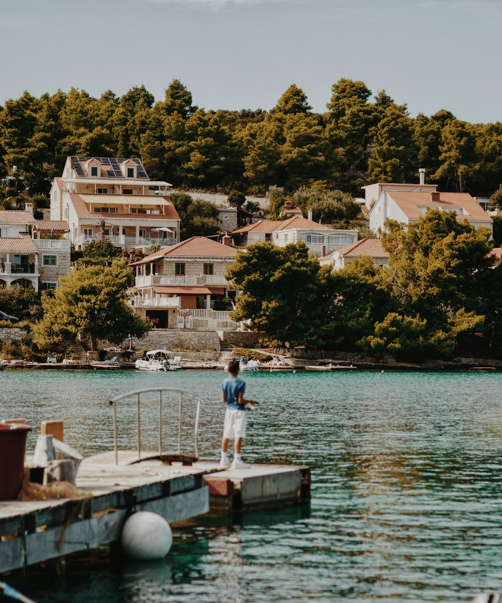 a man standing on a dock next to a body of water