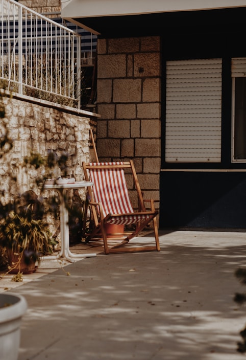 A cozy patio chair with a plush outdoor back cushion in soft earth tones under natural sunlight.