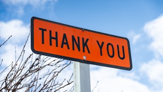 A hopeful veteran smiling warmly while holding a 'Thank You' sign outdoors.