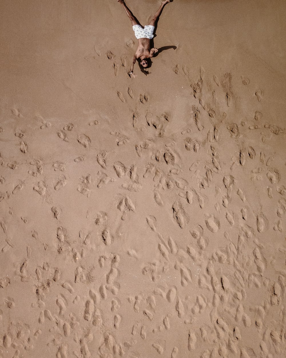 eine Person, die in der Mitte eines Sandstrandes steht