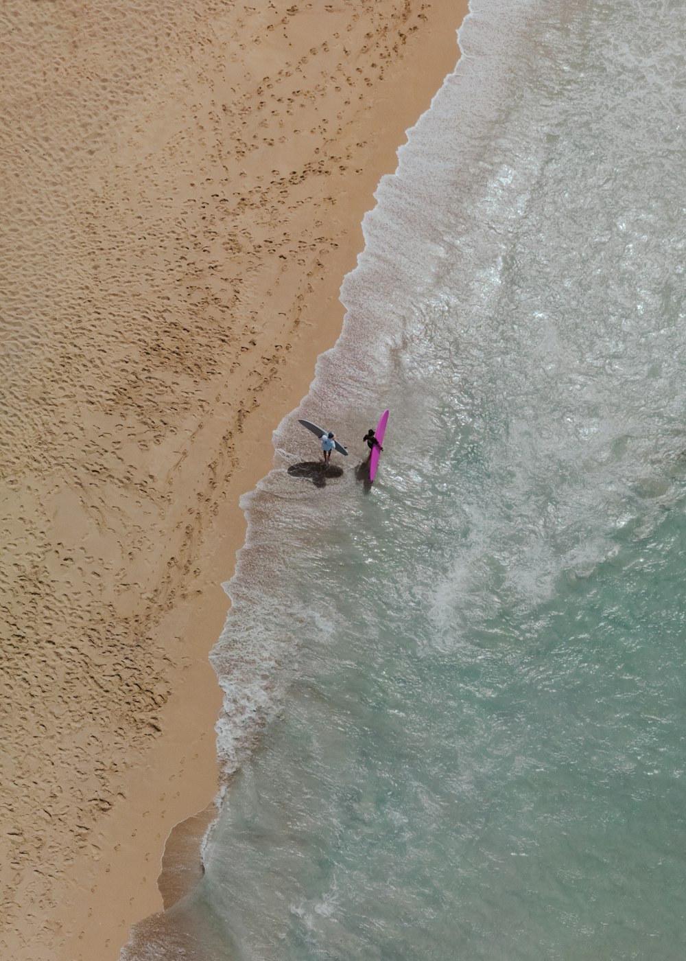 a couple of people standing on top of a beach next to the ocean